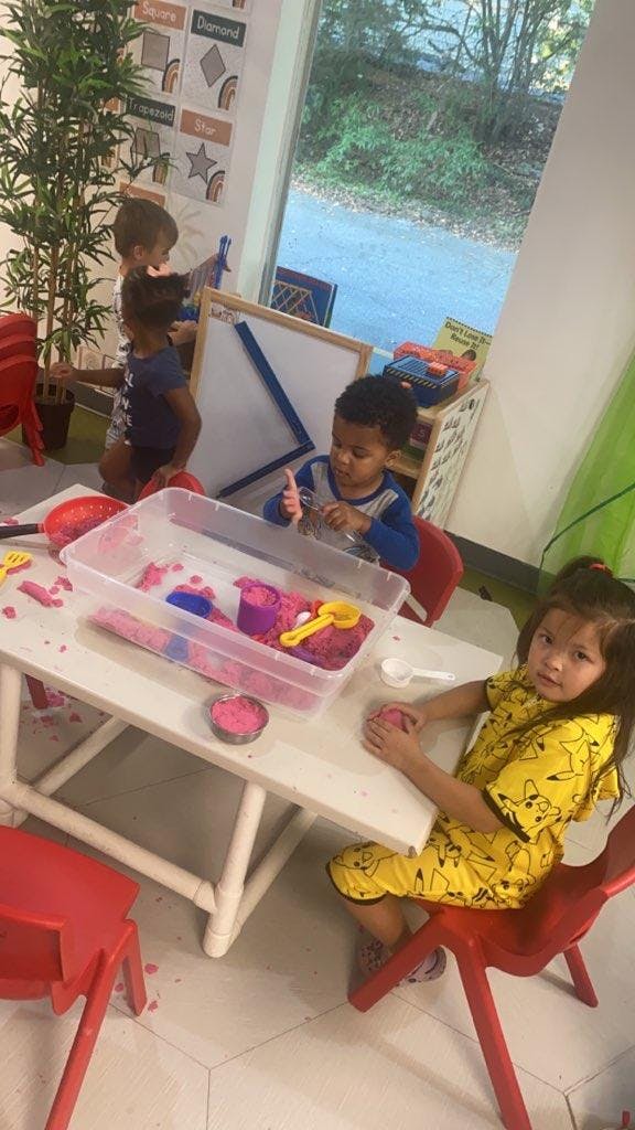 Children playing with kinetic sand at a table