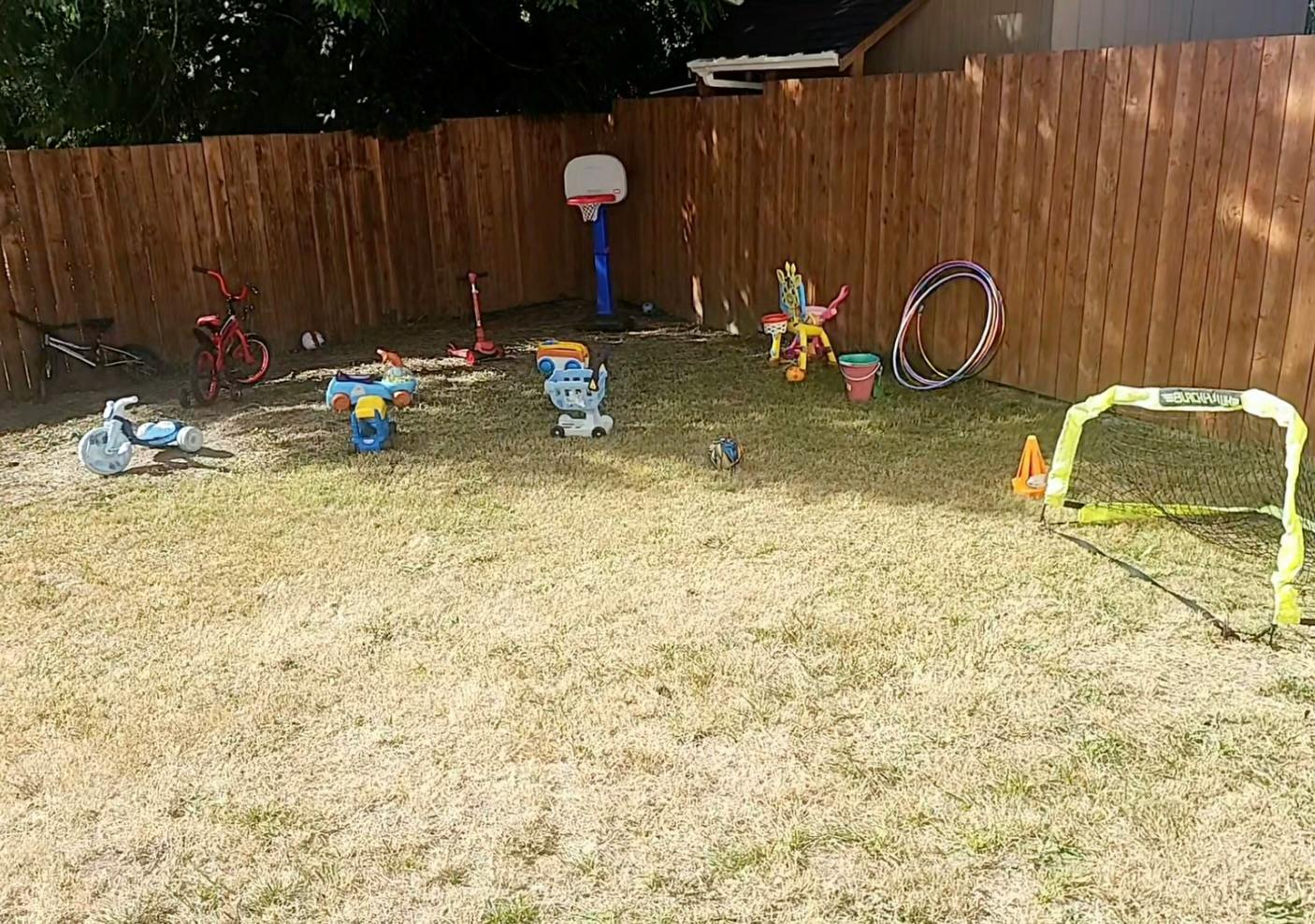 Collection of children's toys and sports equipment scattered in a backyard