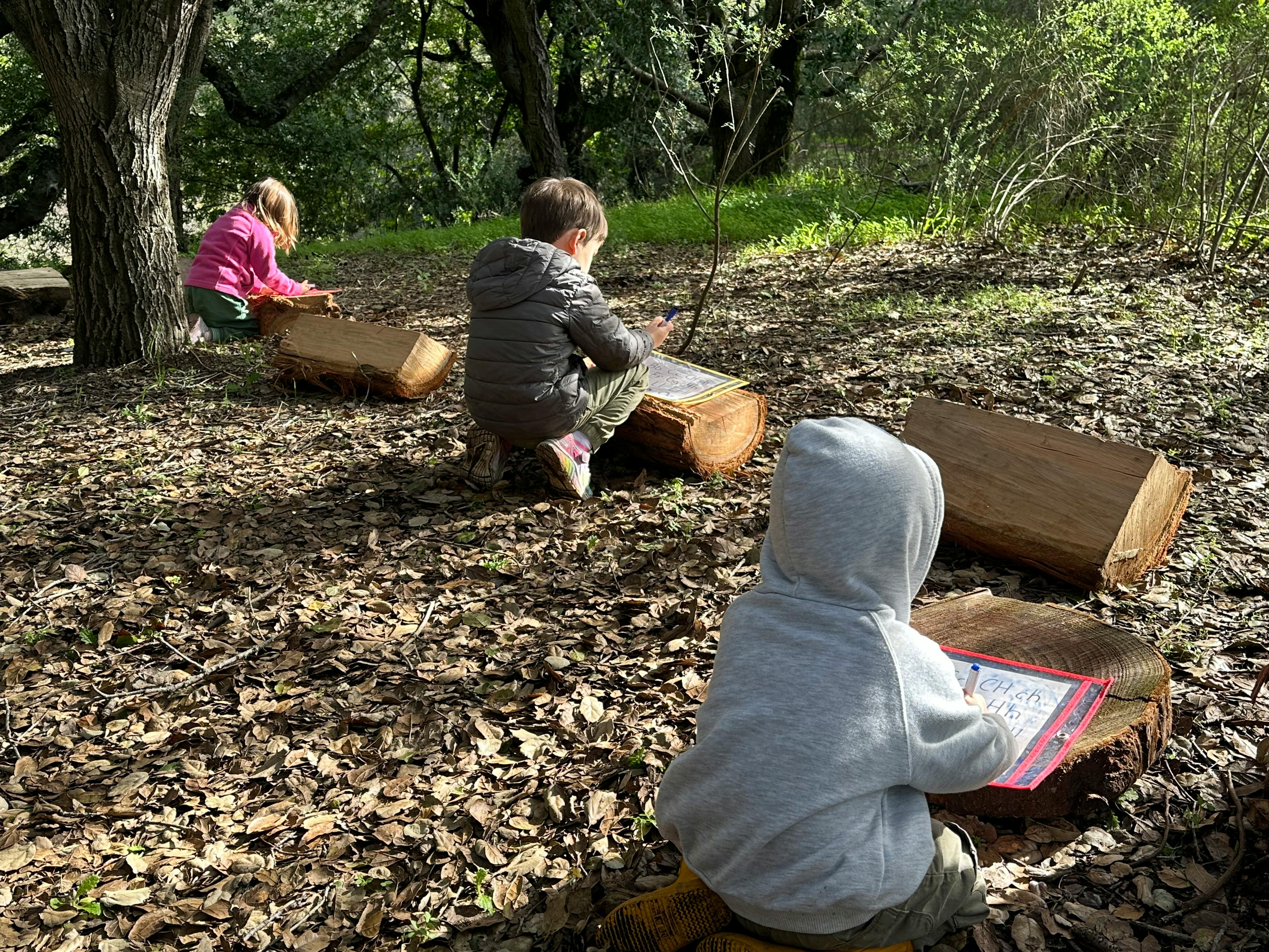 Three children drawing outdoors