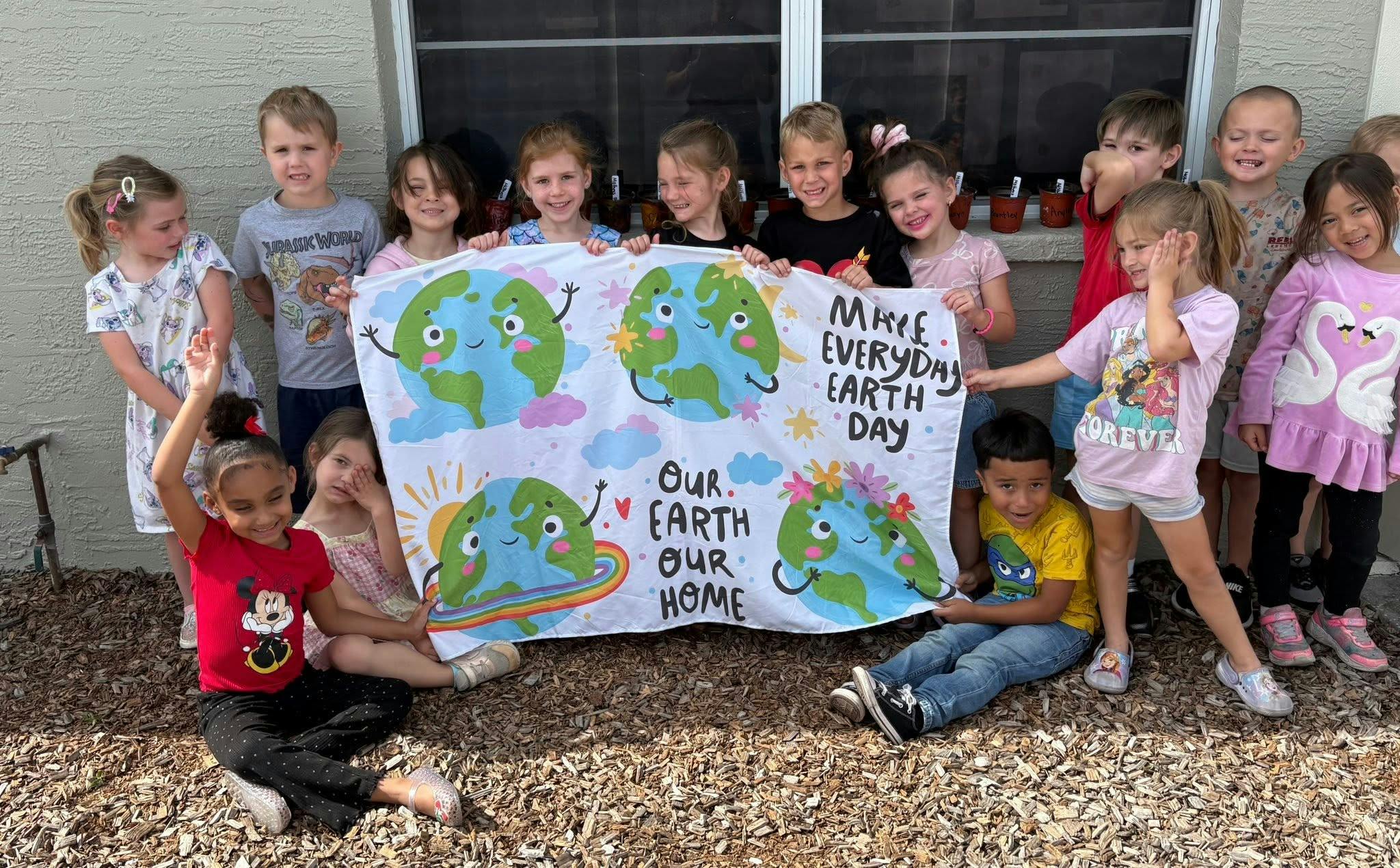 Group of children holding an Earth Day poster outdoors