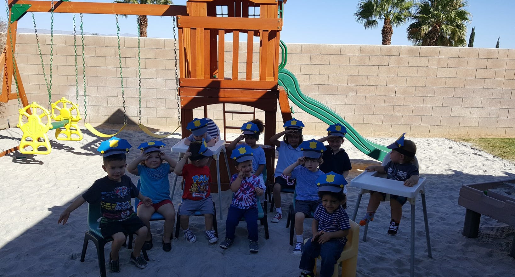 Children wearing hats sitting on chairs on a playground