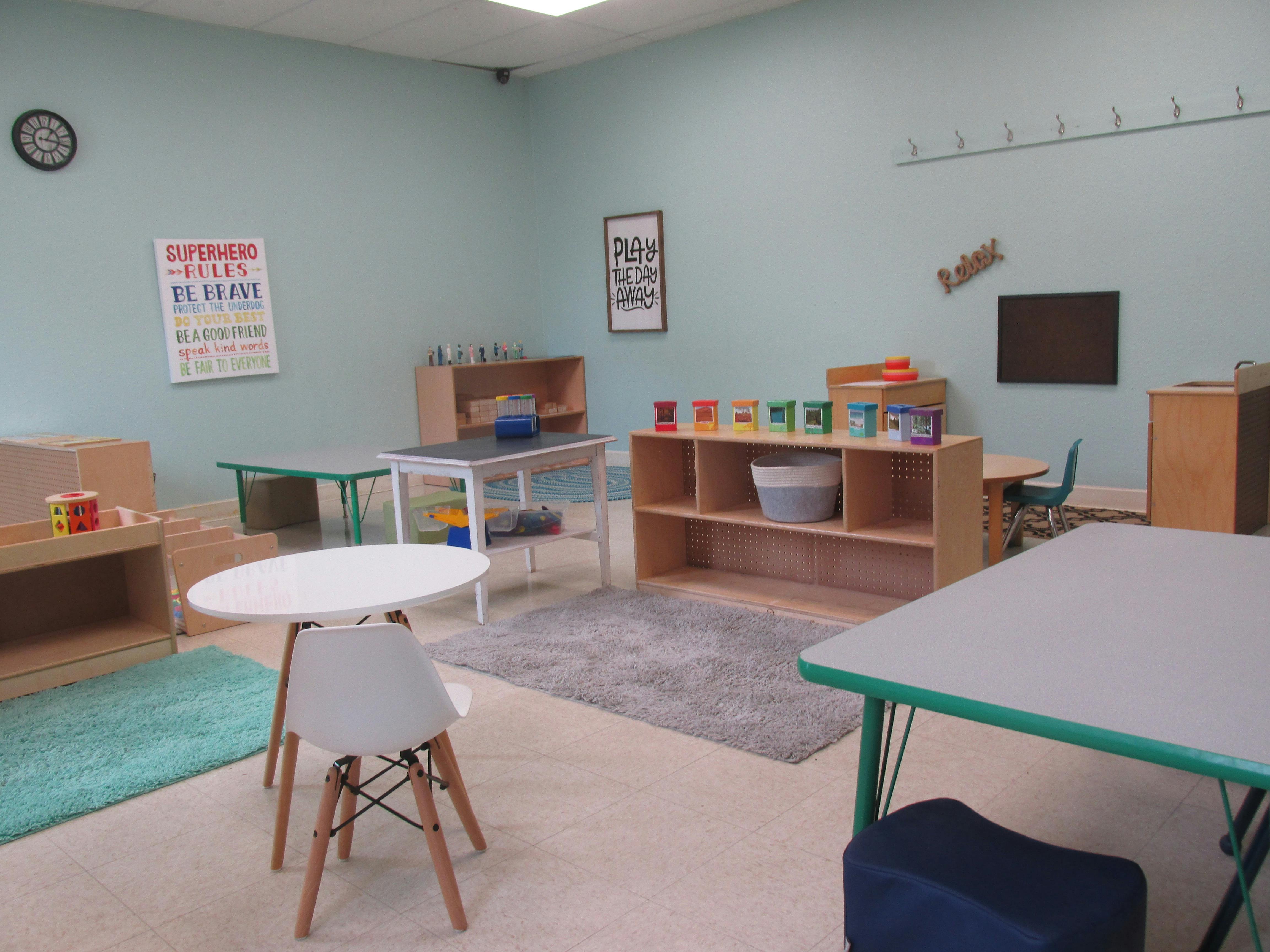 Classroom with small tables, chairs, and shelves