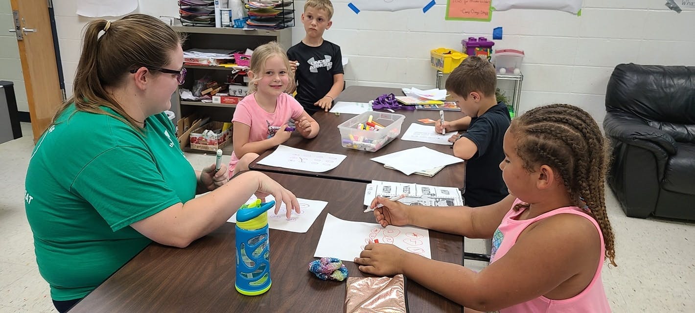 Adult and children sitting at a table with papers
