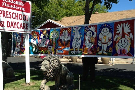 Sign for "Preschool & Daycare" with a lion statue and colorful banner