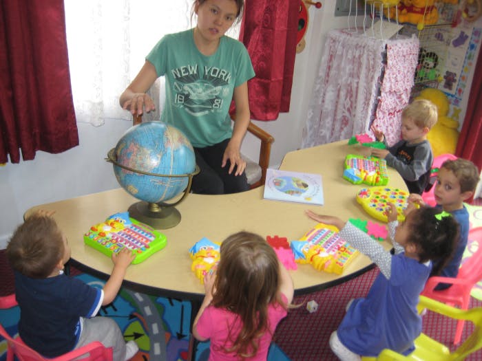 Person showing a globe to children at a table
