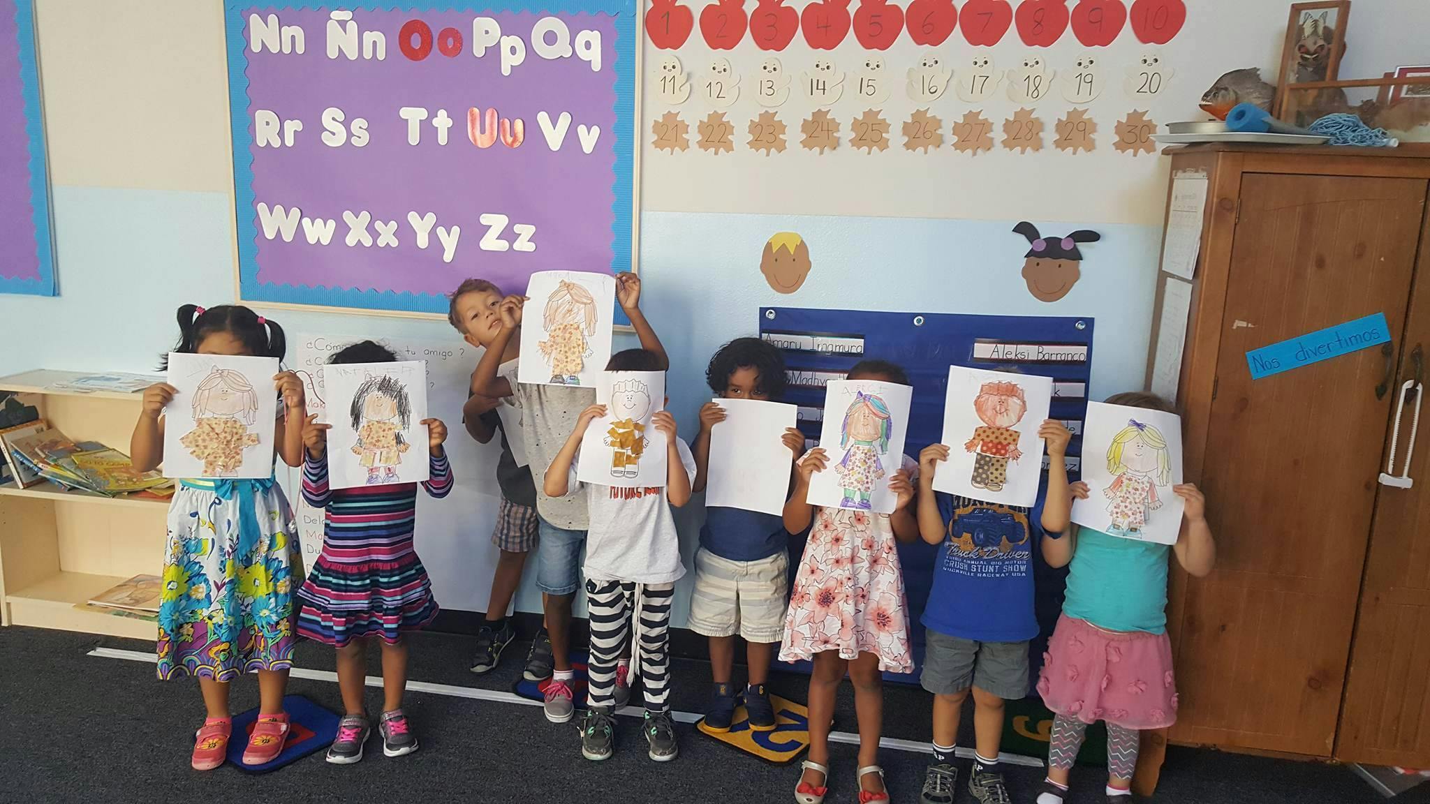 Children holding up drawings in a classroom