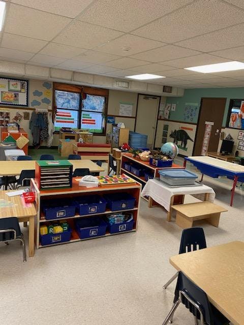 Empty classroom with small tables, chairs, and learning materials