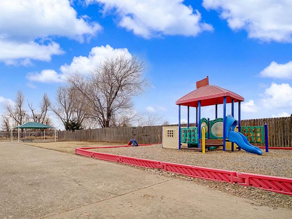 Playground with a slide and a small covered area under a blue sky