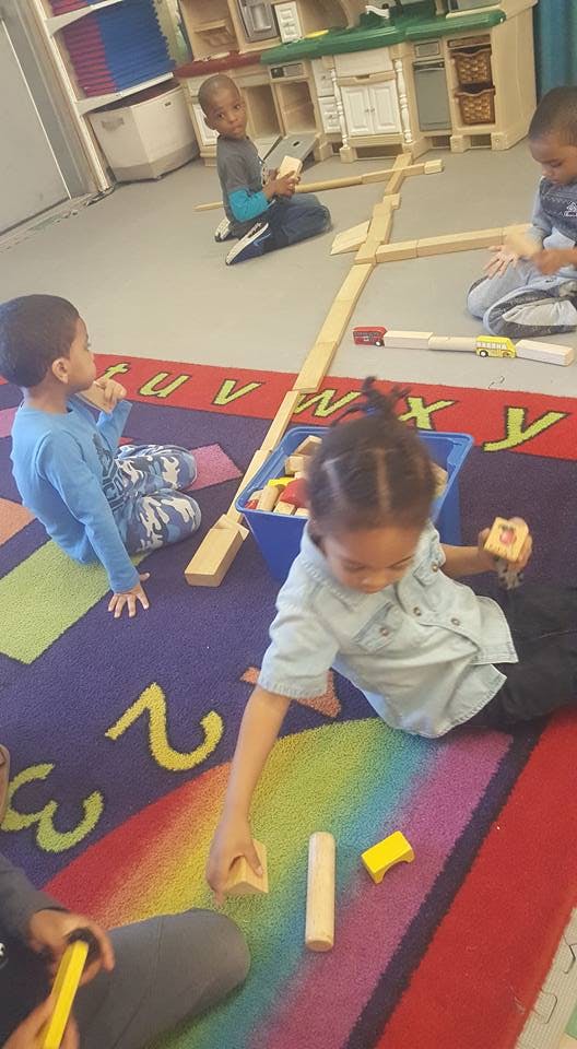 Children playing with wooden blocks on a colorful rug