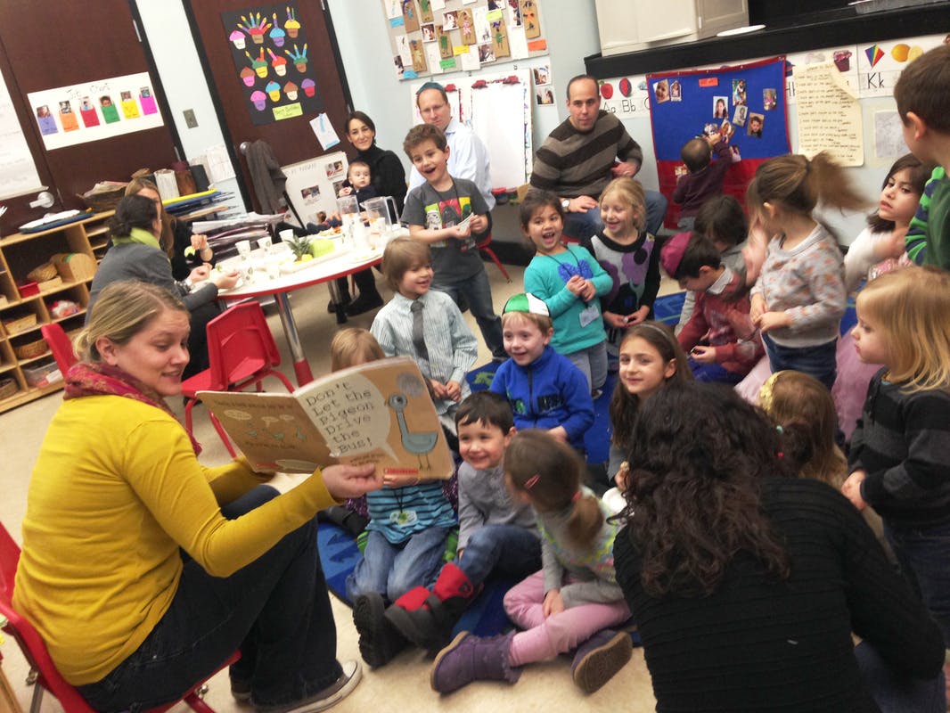Person reading a book to a group of children in a classroom