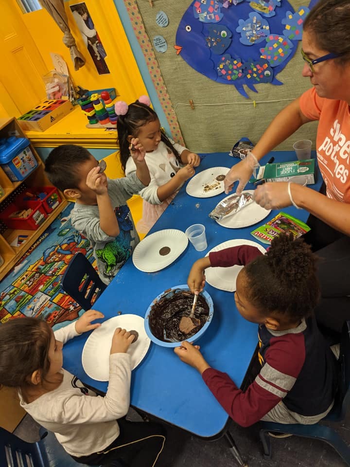 Adult and children at a table making a craft with chocolate mixture