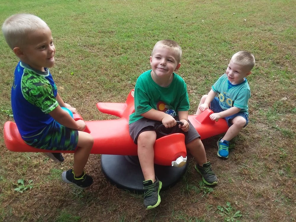 Three children on a red airplane-shaped seesaw