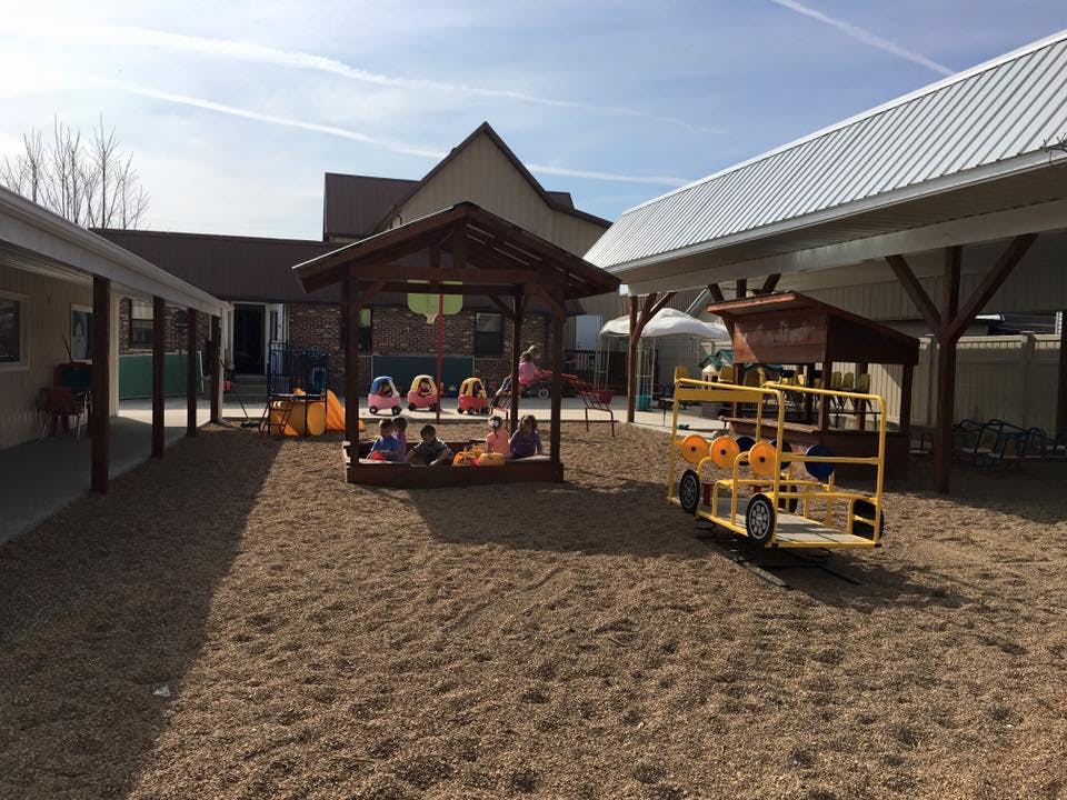 Children playing in a sandbox under a gazebo