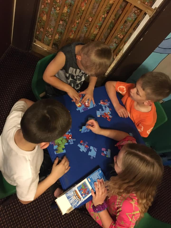 Four children assembling a puzzle on a blue table