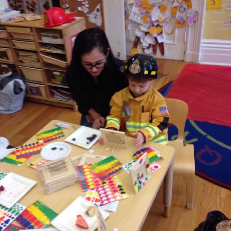 Adult and child in firefighter costume looking at a small screen at a table