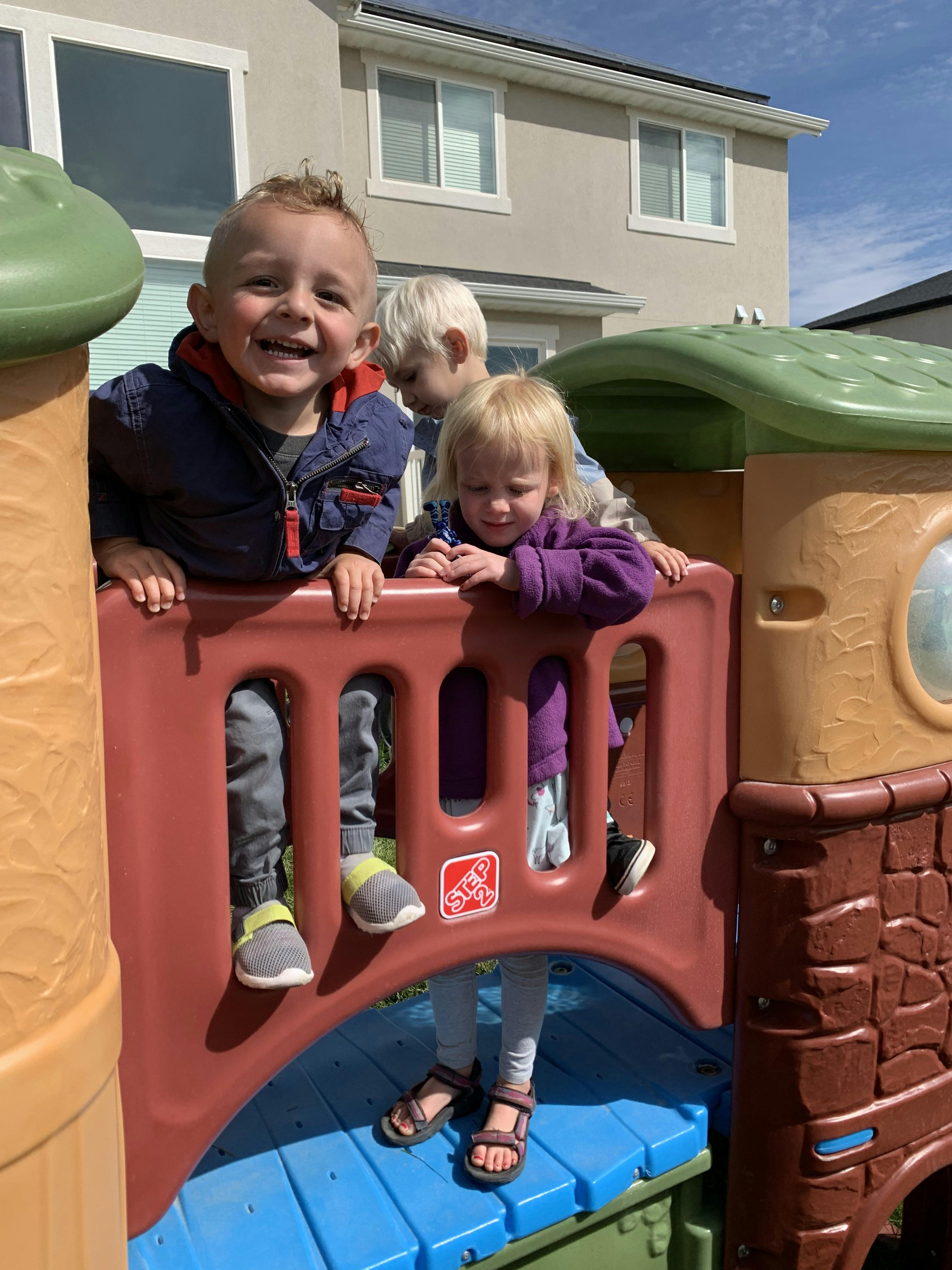 Three children playing on a plastic play structure