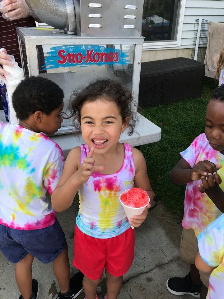 Child holding a Sno-Kones cup, with other children nearby