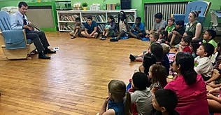 Person reading to a group of children in a classroom