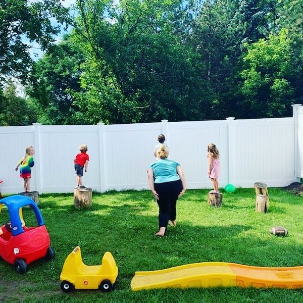 Person and children playing with a ball in a grassy yard