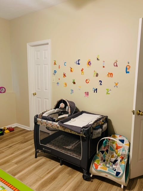Nursery room with a playard, baby bouncer, and alphabet wall decals