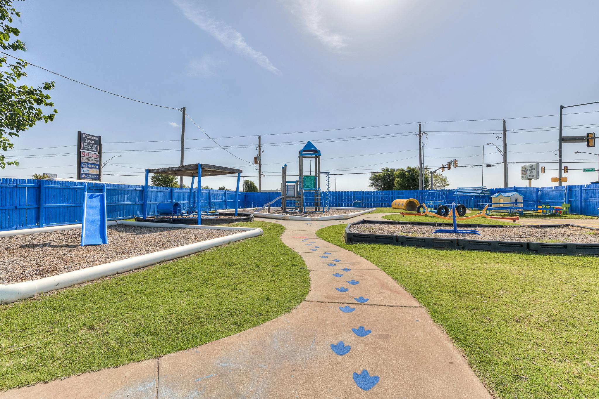 Outdoor playground with slides, swings, and a path with blue footprints