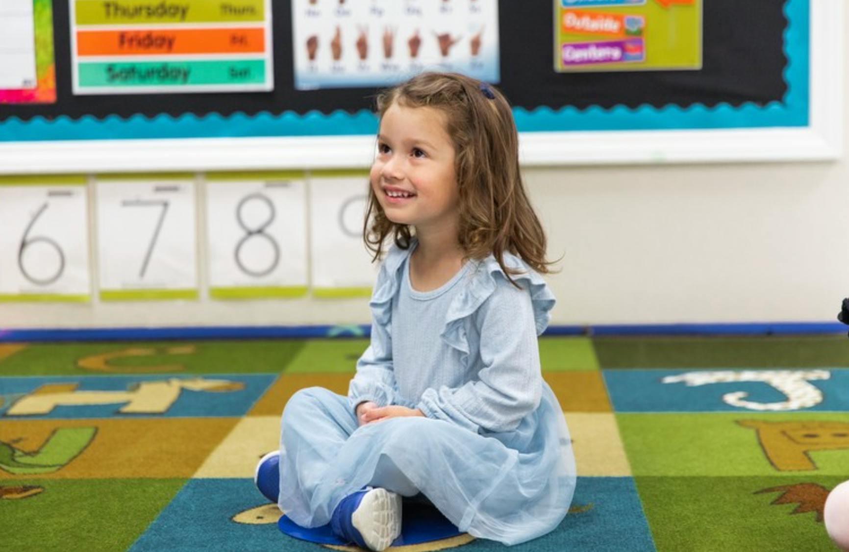 Child sitting on a carpet in a classroom