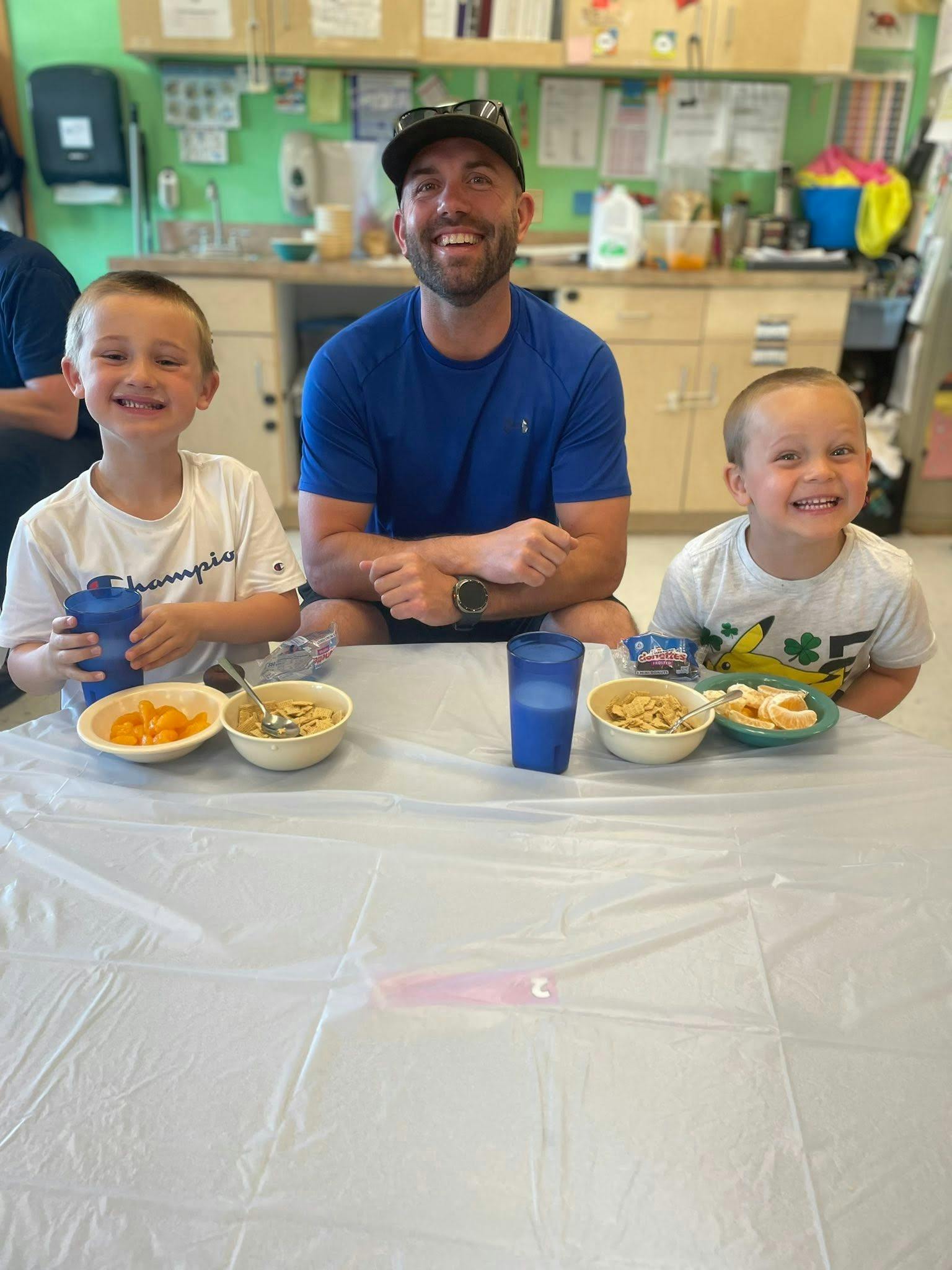 An adult and two children sitting at a table with breakfast food