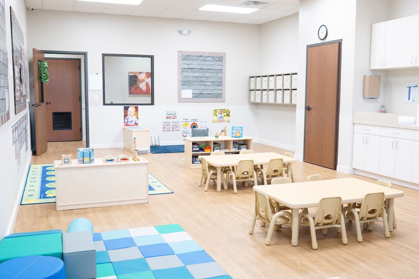 Empty preschool classroom with child-sized tables and floor mats