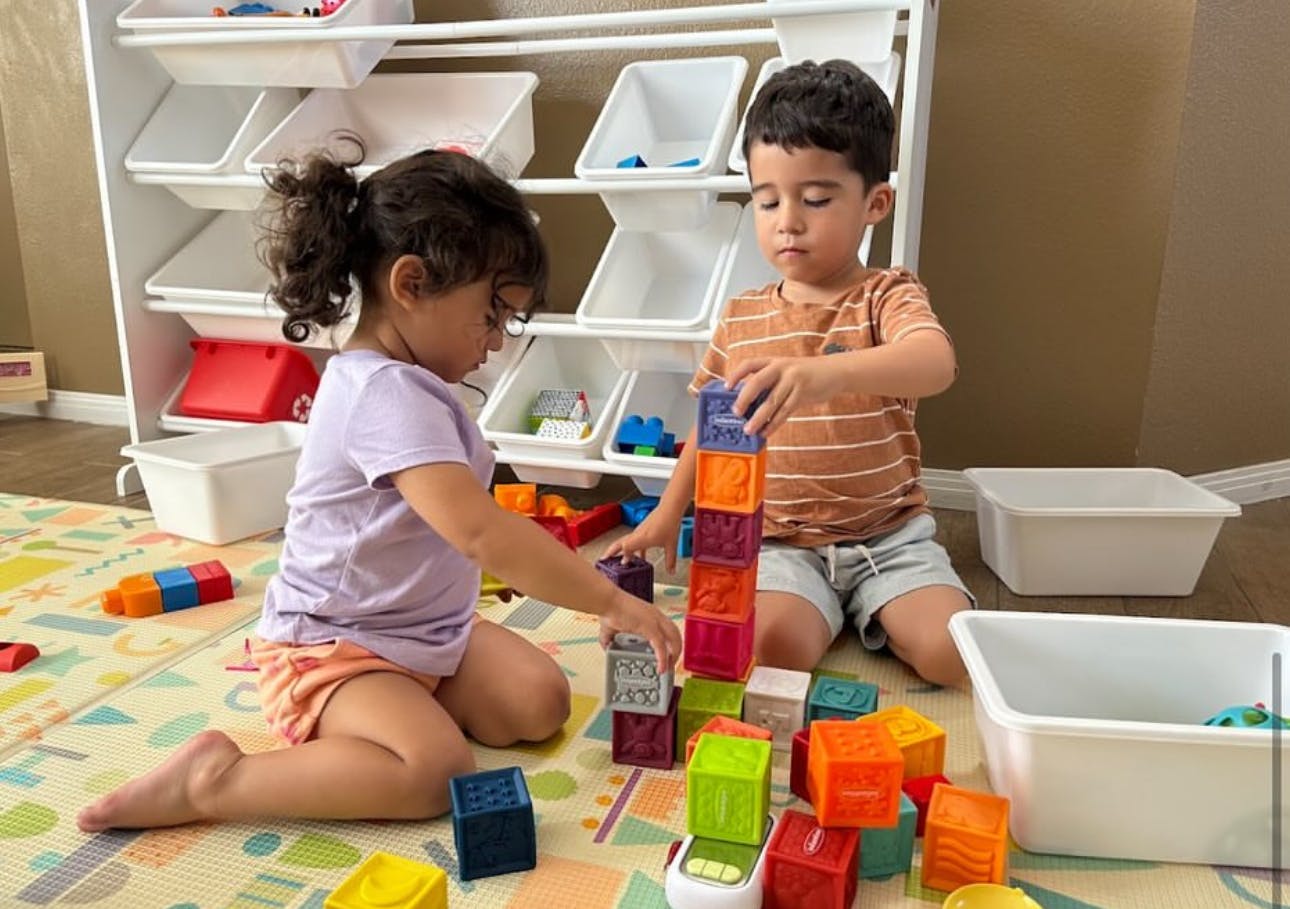 Two children playing with colorful building blocks on the floor