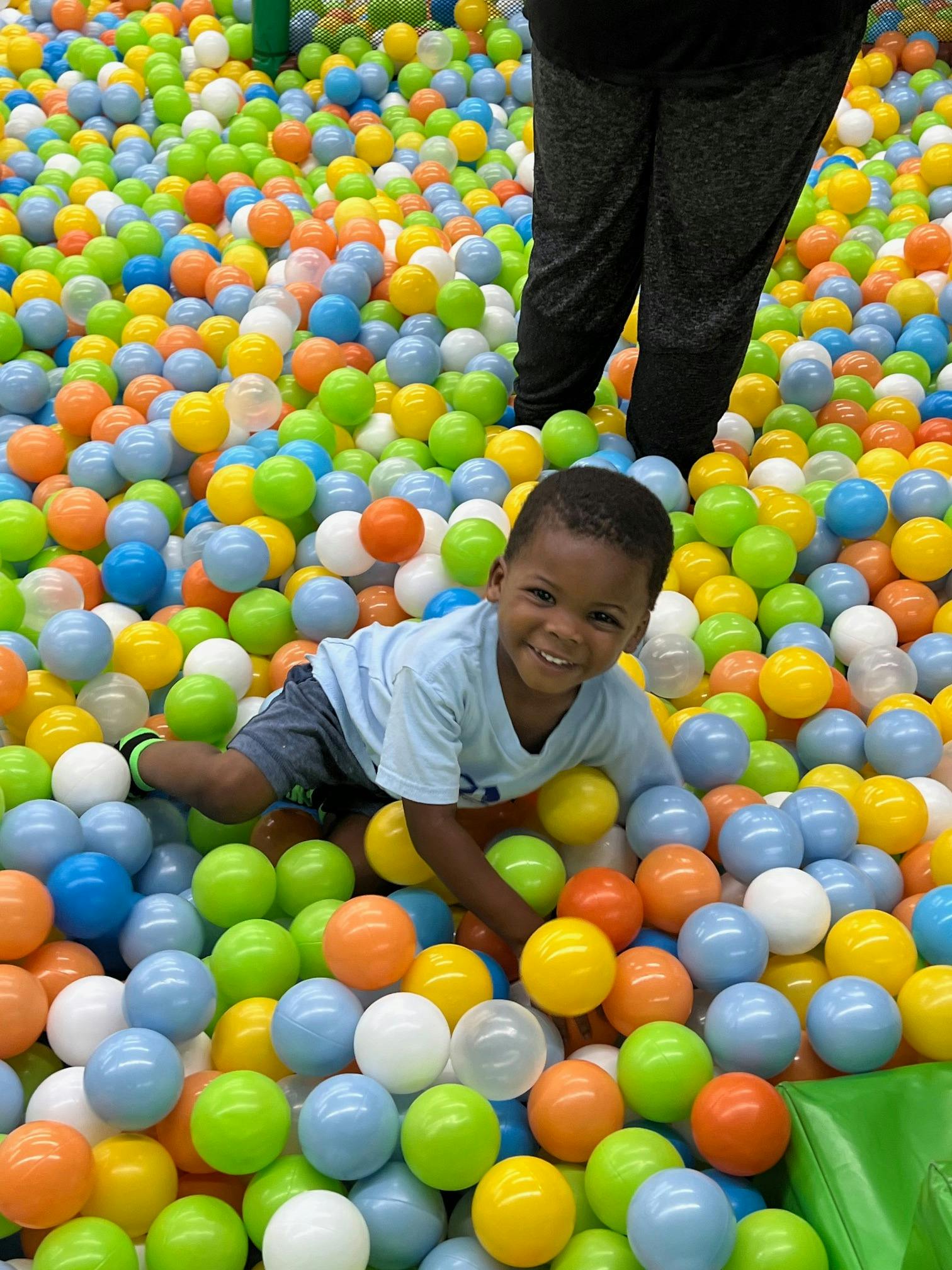 Child smiling while lying in a ball pit