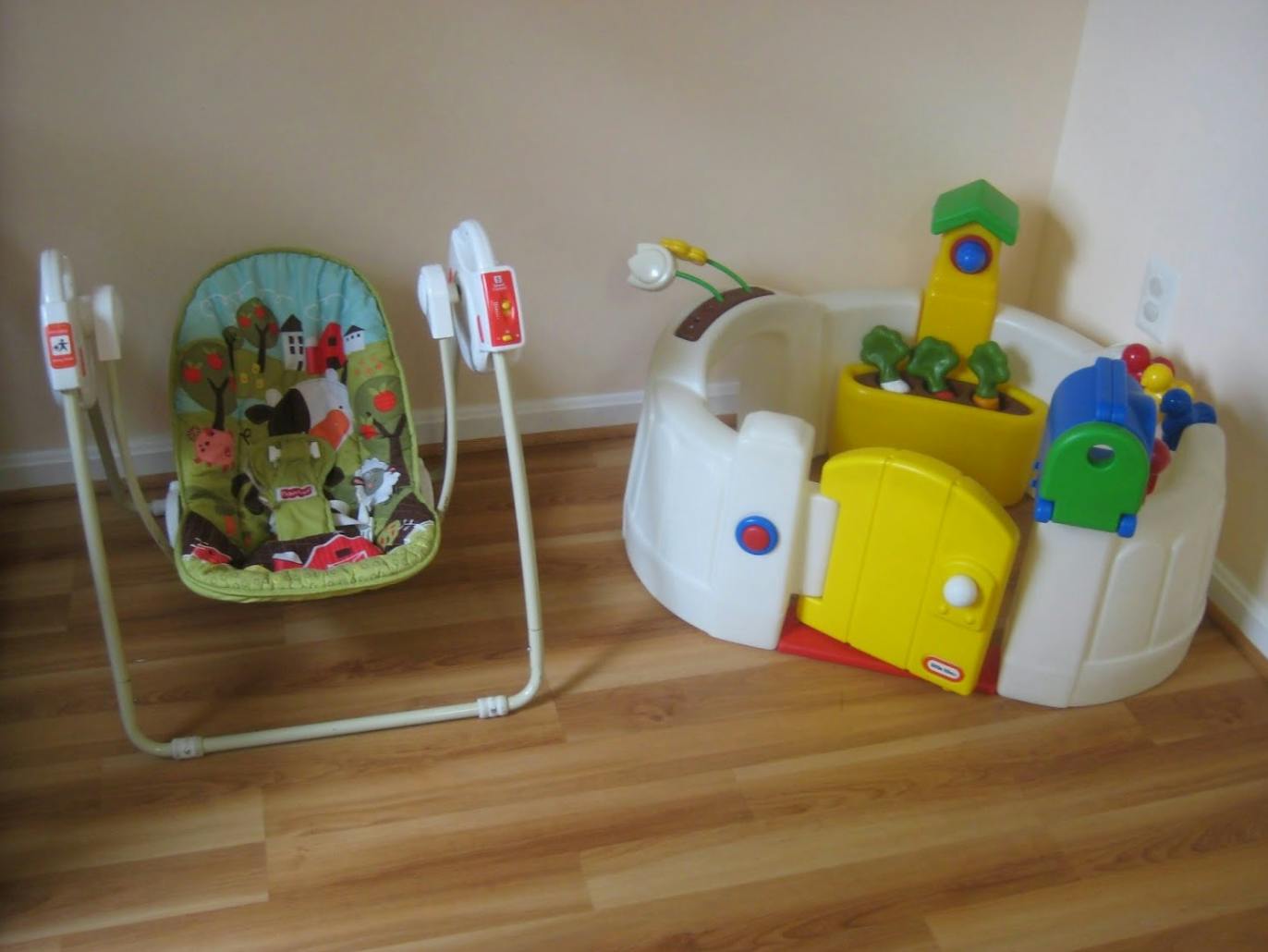 Baby swing and activity center on a wooden floor