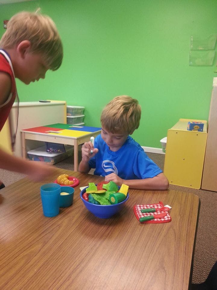 Two children playing with toy food at a table
