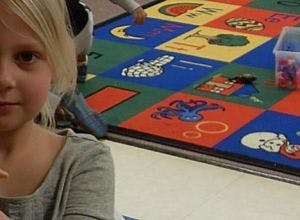 Child in foreground with colorful alphabet rug in background