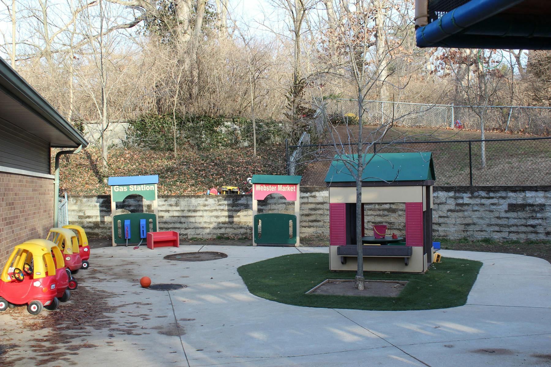 Outdoor play area with toy cars, playhouses, and a small tree