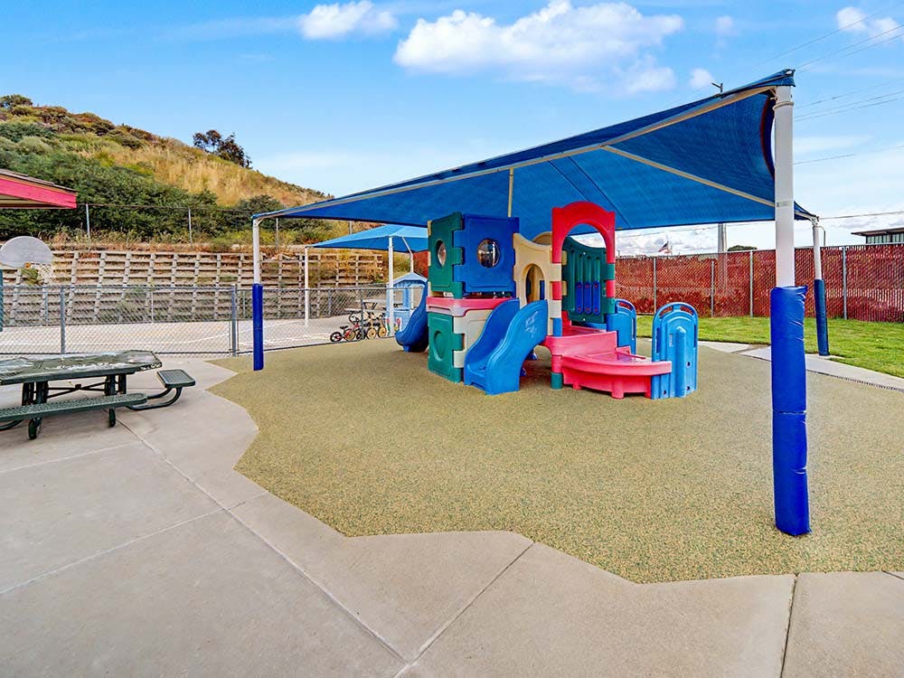 Colorful outdoor playground with slides under a blue sunshade