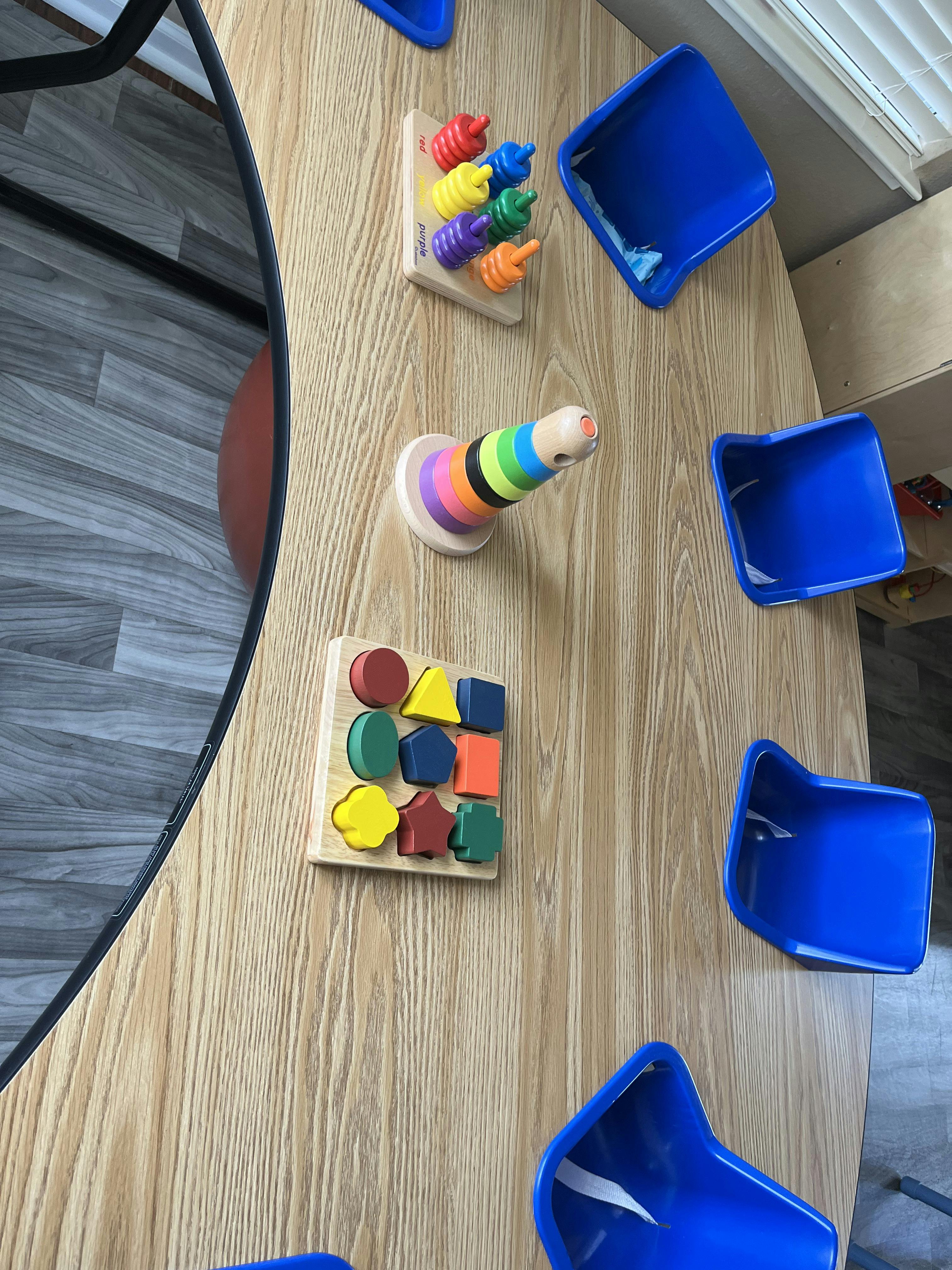 Shape sorter, stacking rings, and peg toy on a wooden surface