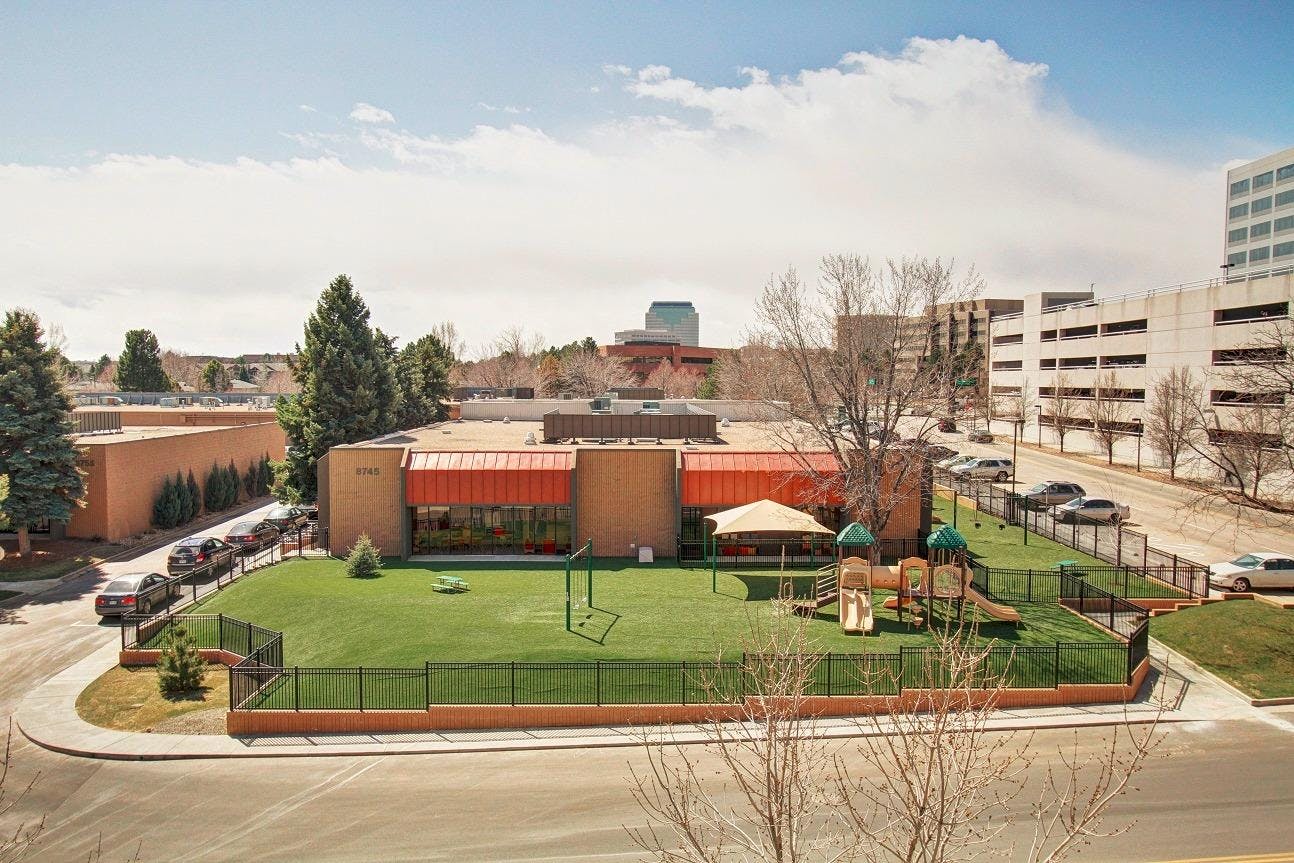 Building with a fenced playground and green lawn