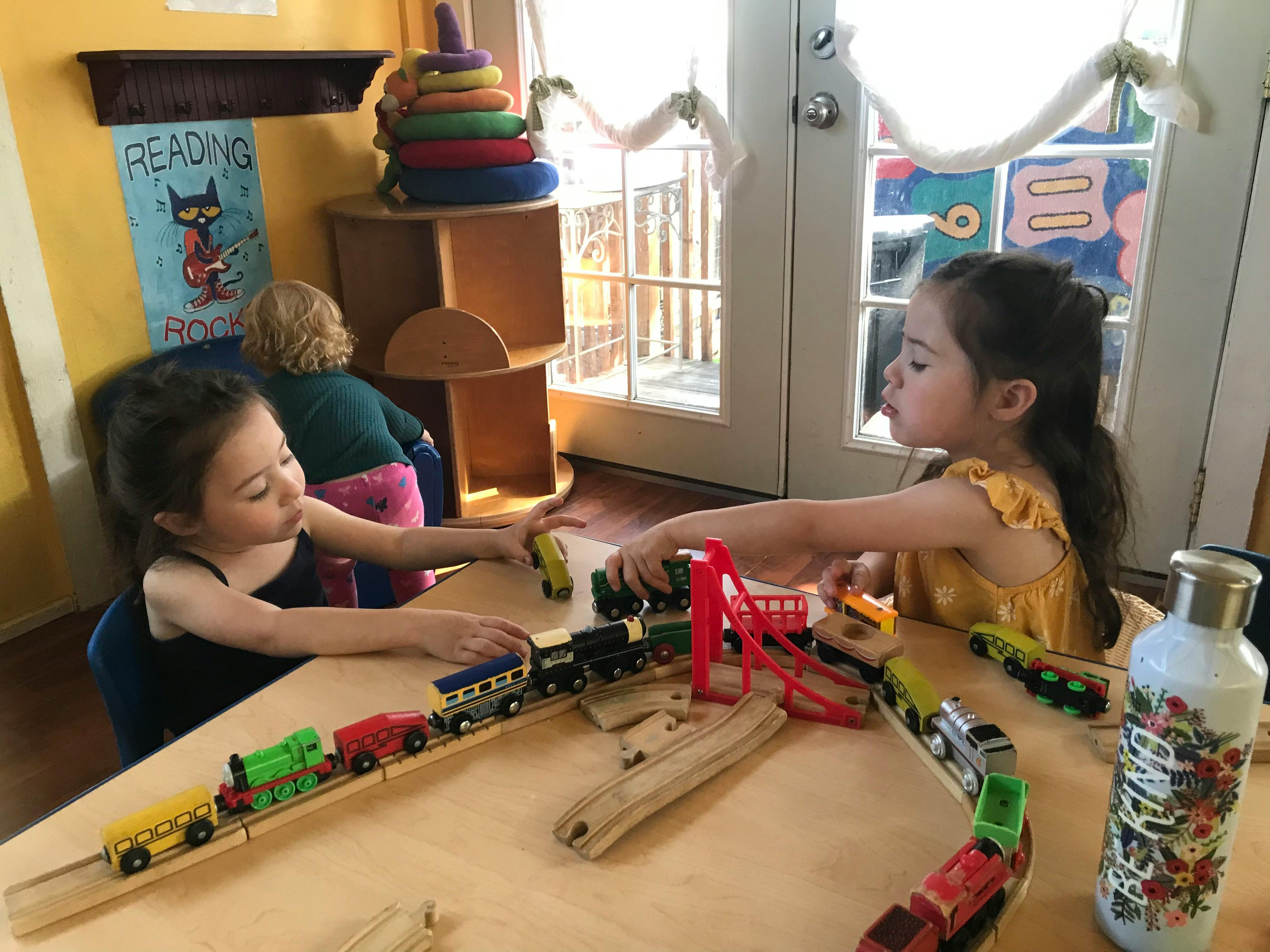 Two children playing with toy trains on a table