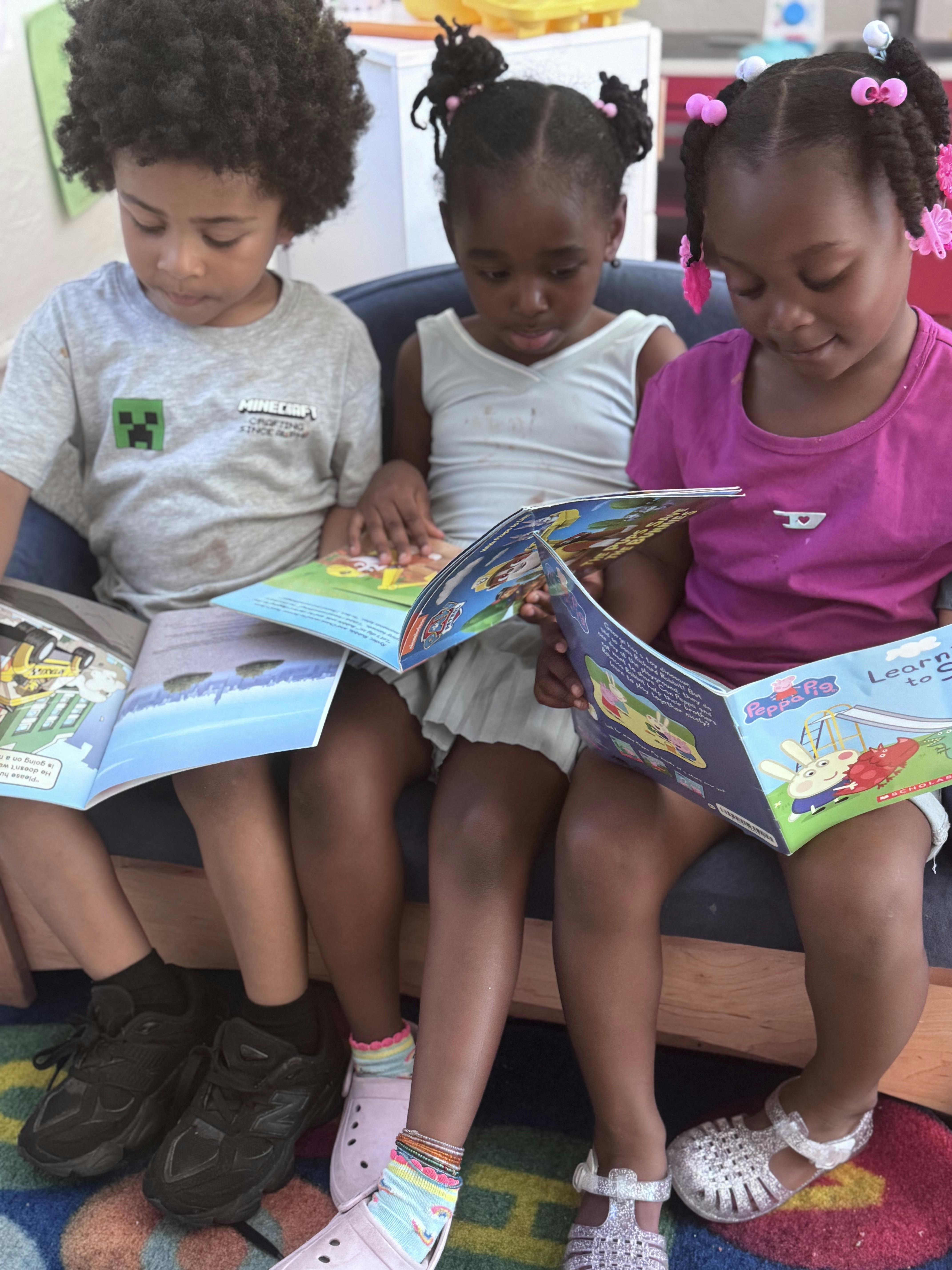 Three children sitting together and reading books