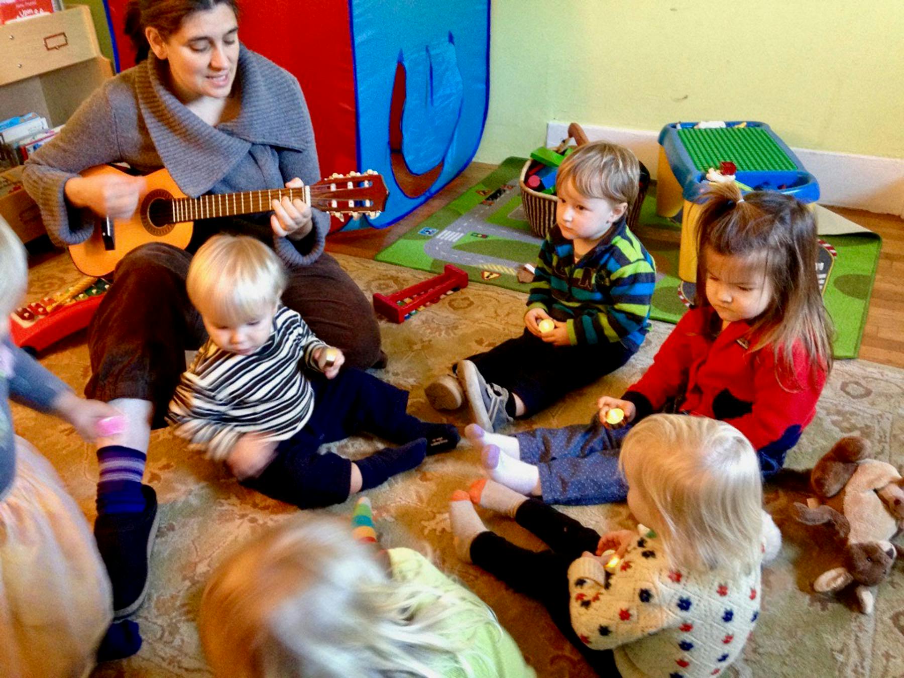 Person playing a ukulele for a group of children