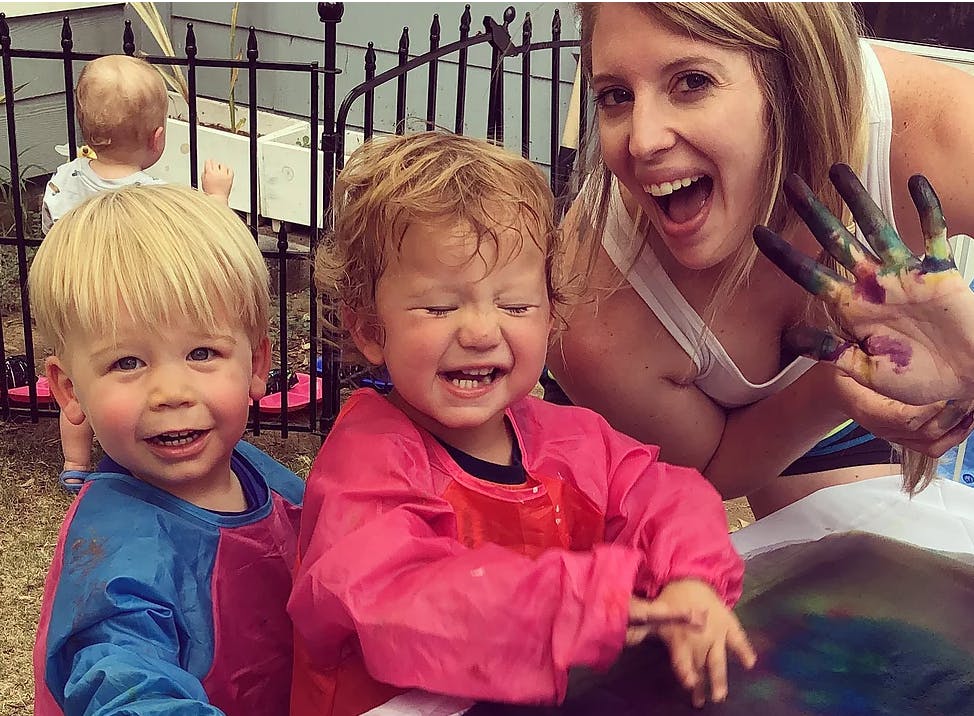 Two children in smocks and a person with paint on their hands