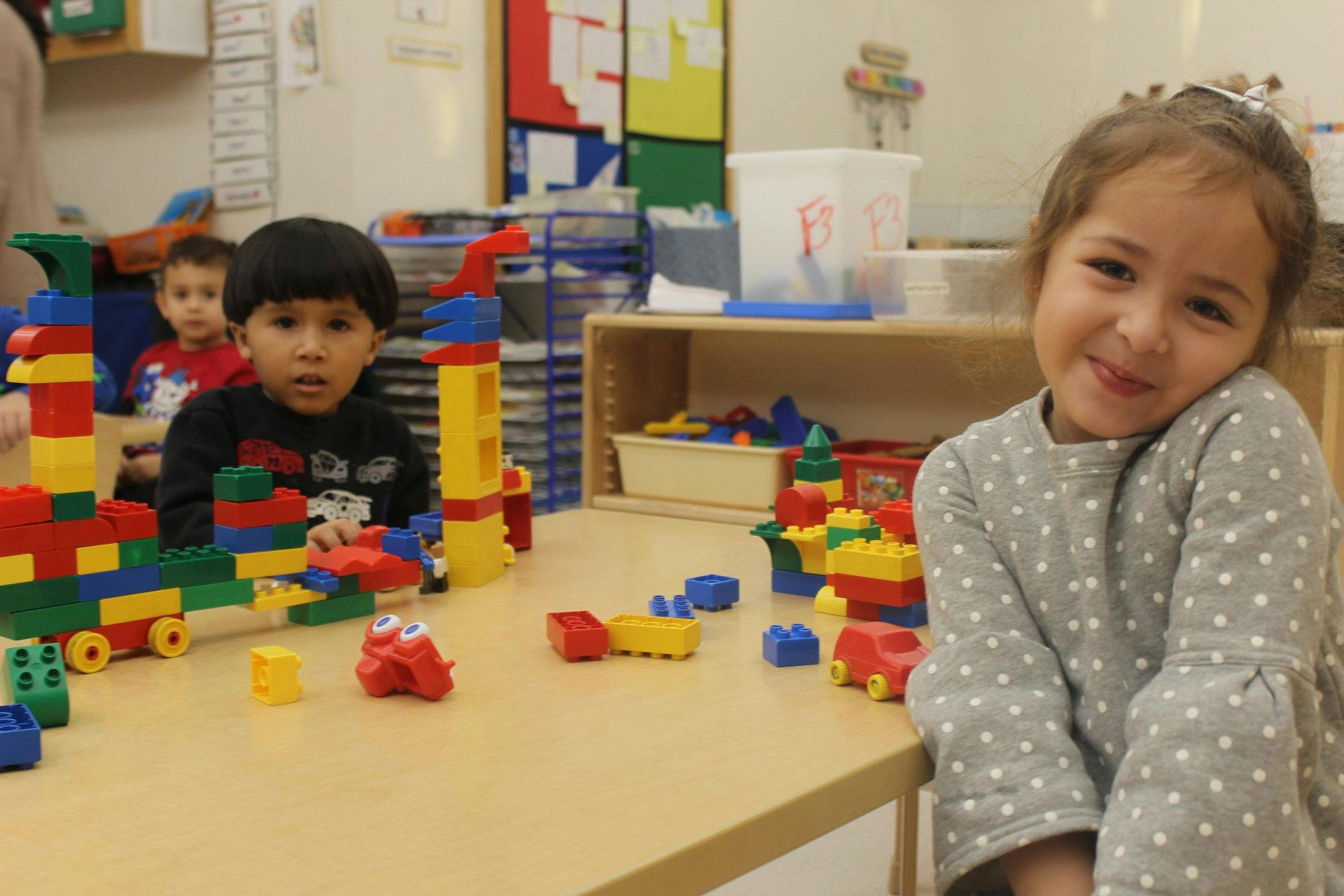 Two children playing with colorful building blocks at a table