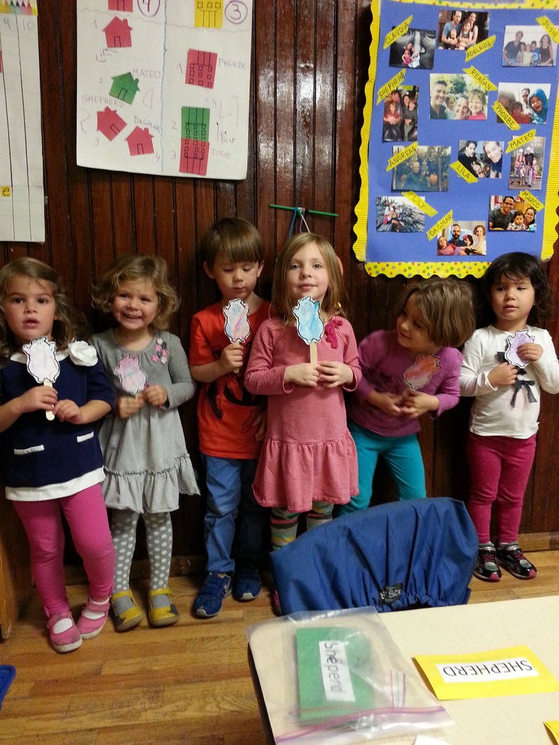 Six children holding up paper crafts in a classroom