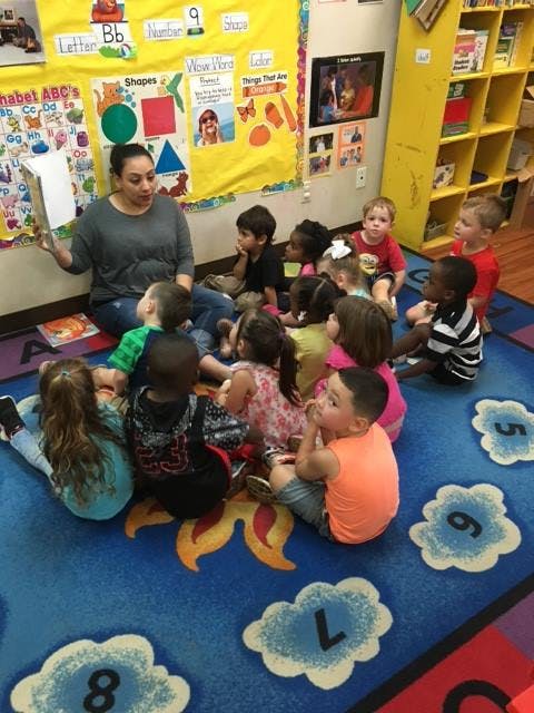 Person reading to a group of children in a classroom