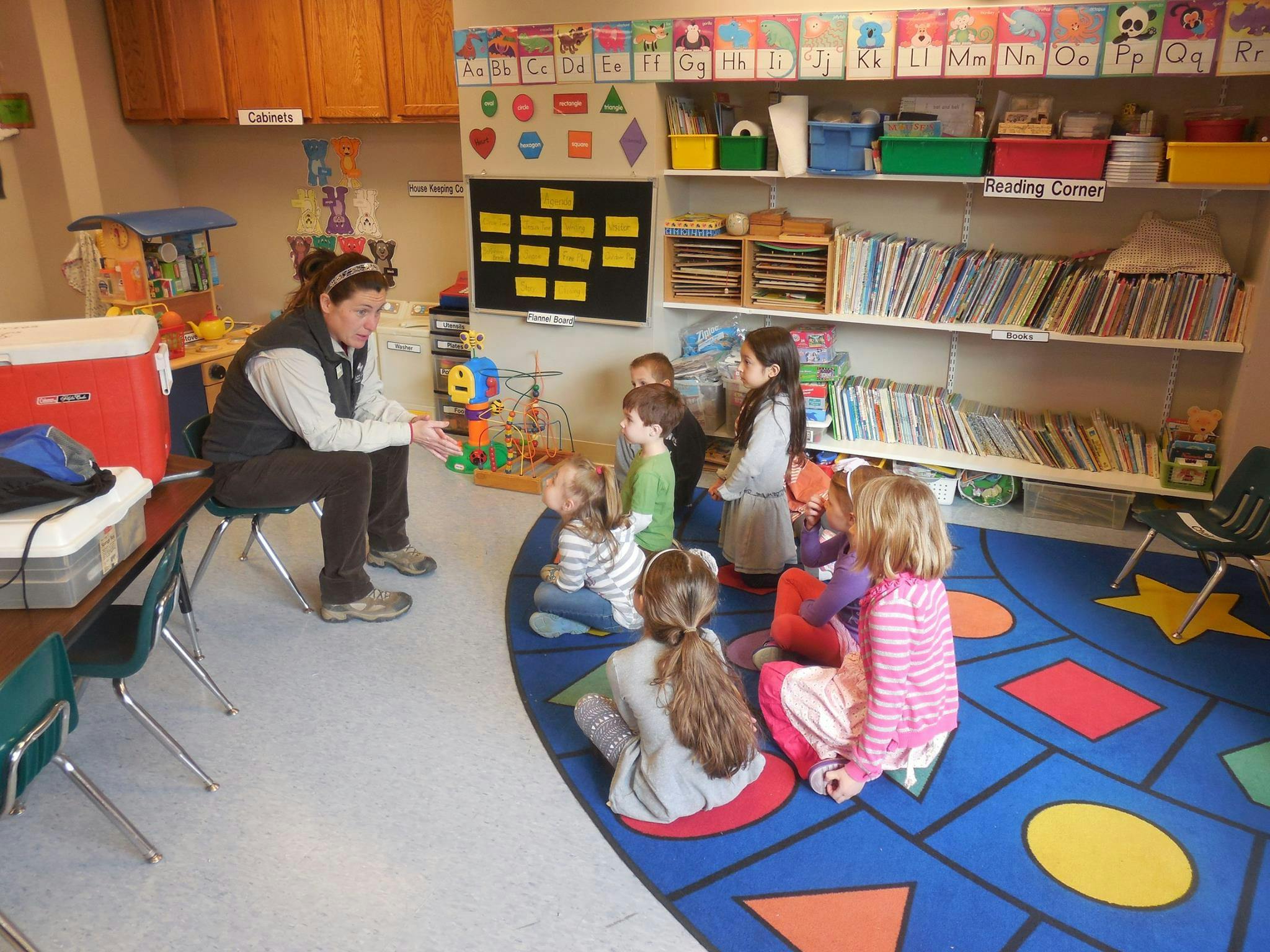 Adult and children sitting on a rug in a classroom