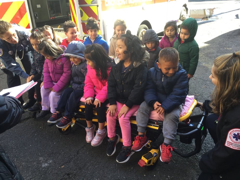 Children sitting on a stretcher with two adults nearby