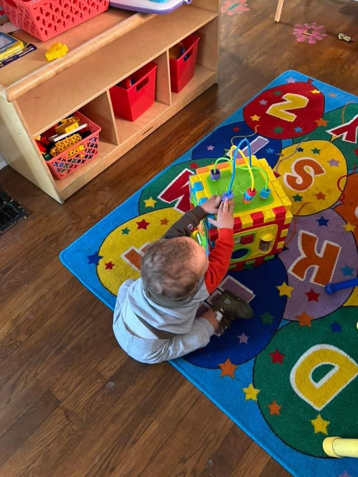 Child playing with an activity cube on a colorful rug