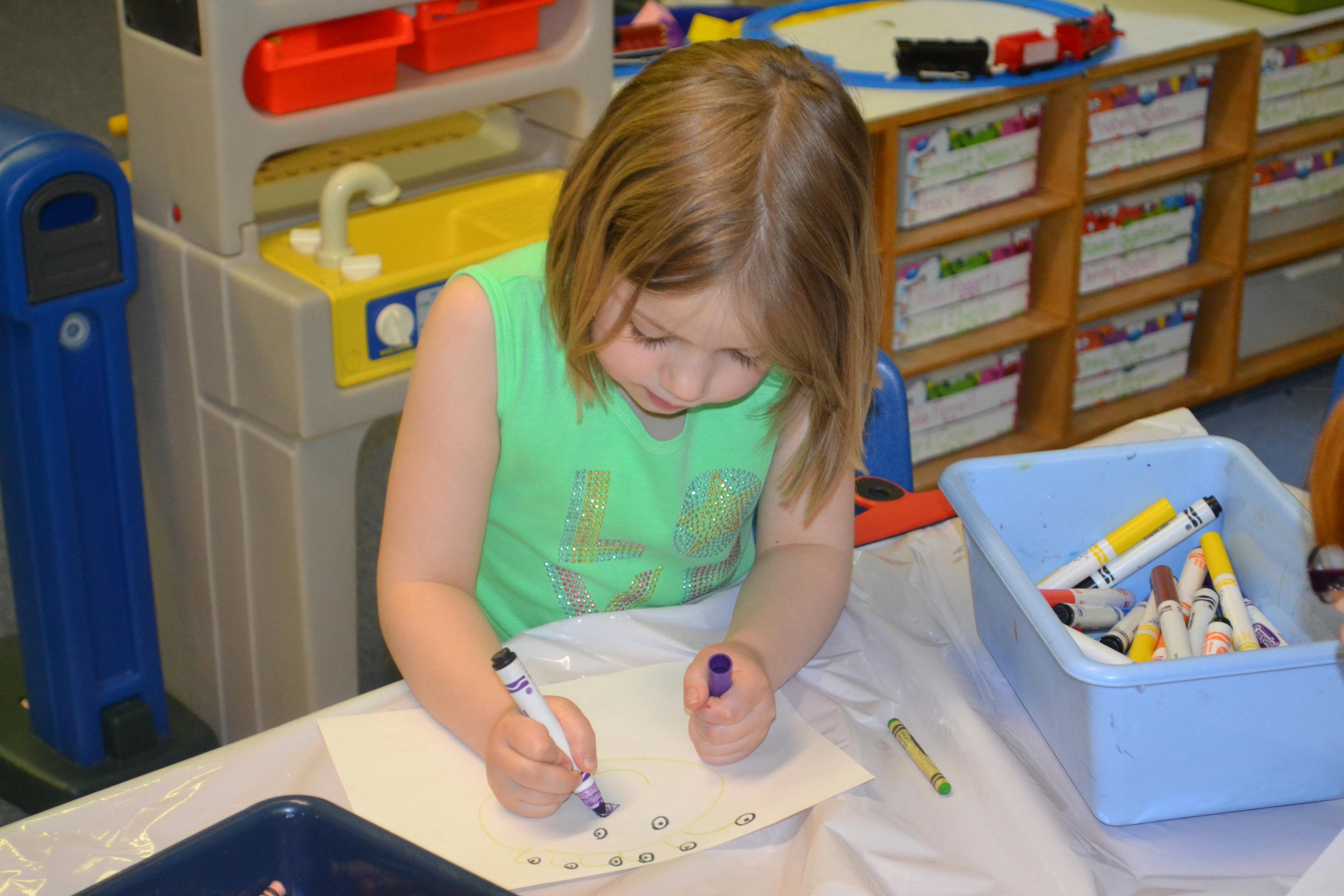 Child drawing on paper with markers