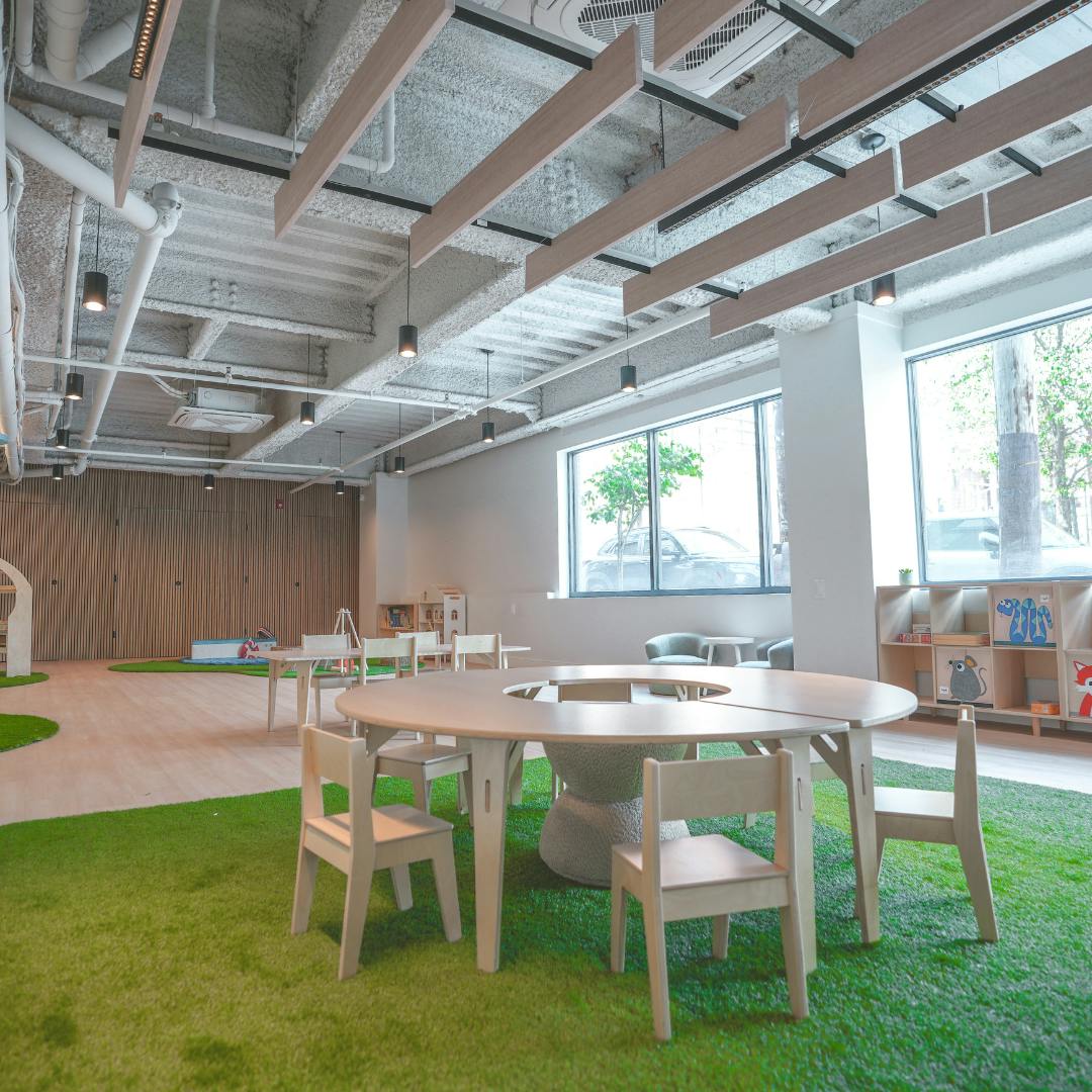 Indoor play area with green turf flooring and small tables and chairs