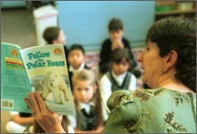 Adult reading a book to children in a classroom